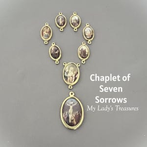 May include: A gold-toned Chaplet of Seven Sorrows rosary. The oval-shaped beads feature religious imagery in muted tones. The text "Chaplet of Seven Sorrows My Lady's Treasures" is visible.