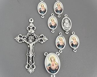 May include: A silver rosary with a crucifix and oval-shaped beads featuring images of the Virgin Mary and the Sacred Heart of Jesus.