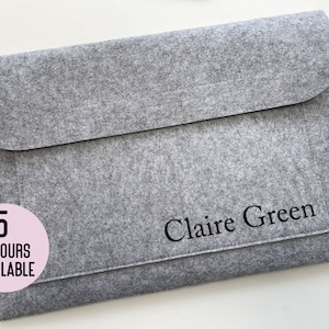May include: Grey felt laptop sleeve with a black flap and a black inscription that reads "Claire Green". A pink circle with the text "5 colours available" is in the bottom left corner.