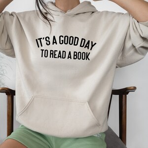 May include: A cream-colored hoodie with a black print that reads "It's a good day to read a book."