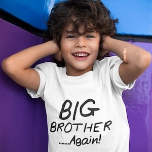 May include: A young child wearing a white t-shirt with the words "BIG BROTHER Again!" printed in black. The child is smiling and has their hands up near their ears. The background is a mix of blue and purple.