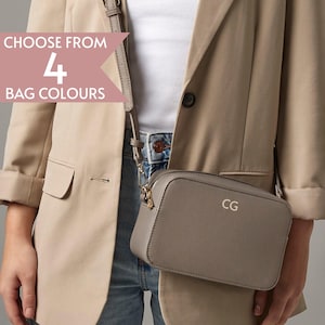 Puede incluir: Un bolso bandolera gris con herrajes dorados y las iniciales "CG" en dorado. El bolso es rectangular y tiene una correa larga y ajustable. La imagen incluye el texto "CHOOSE FROM 4 BAG COLOURS".