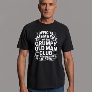 Könnte beinhalten: Schwarzes T-Shirt mit weißem Text: „OFFICIAL MEMBER OF THE GRUMPY OLD MAN CLUB NO NEW MEMBERS ALLOWED“. Das kurzärmlige T-Shirt wird von einer Person getragen.