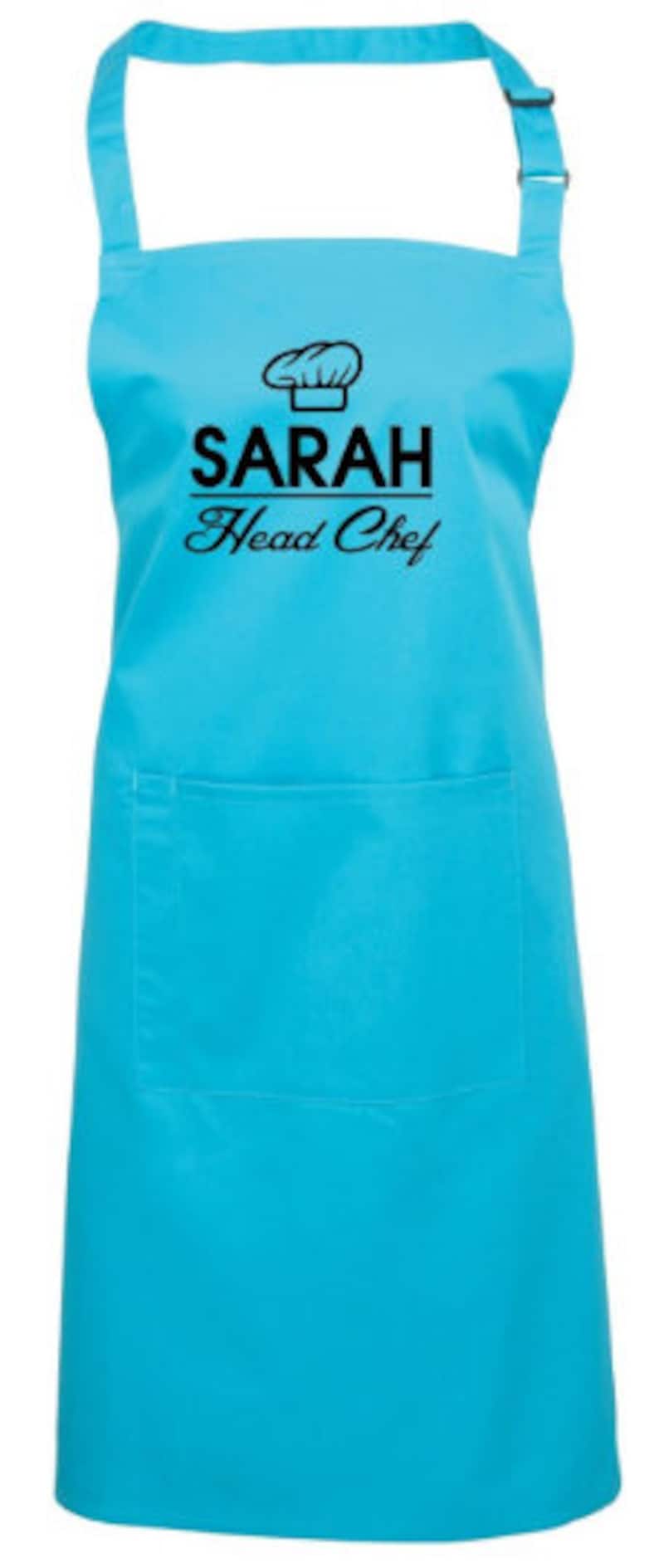 May include: A turquoise blue apron with a black chef's hat graphic and the text "SARAH Head Chef".