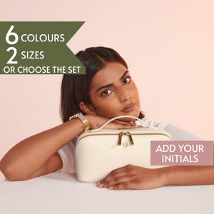 May include: Cream-colored cosmetic bag with gold-toned zipper and handle. The bag has the initials "FB" on the front. Text on the image reads "6 COLOURS 2 SIZES OR CHOOSE THE SET" and "ADD YOUR INITIALS".