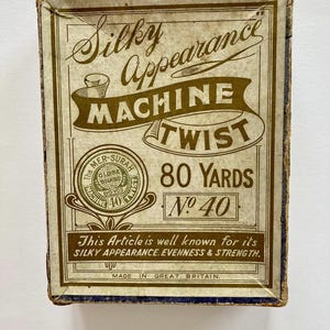 May include: A vintage box of 80 yards of No. 40 "Silky Appearance" machine twist thread. The box is brown with gold lettering and a gold seal with the words "The Mer-Surah Globe Brand" and "Machine Twist 80 Yds No. 40". The text on the box reads "This Article is well known for its SILKY APPEARANCE. EVENNESS & STRENGTH. MADE IN GREAT BRITAIN."