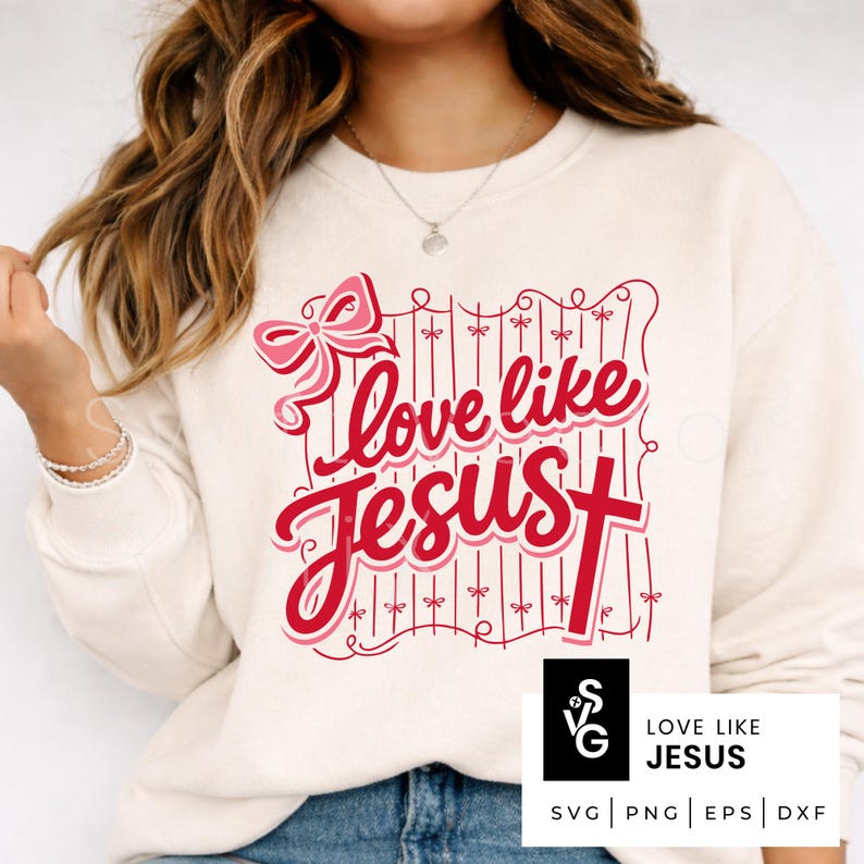 May include: Cream-colored sweatshirt with the phrase "Love like Jesus" in red script. The design includes a pink bow and a cross, with a decorative fence-like border. The bottom right corner features a logo with the text "Love Like Jesus".