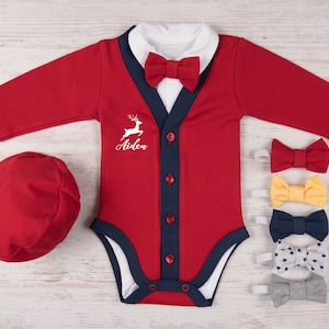 Puede incluir: Un body rojo de manga larga con cuello blanco, tapeta azul marino con cuatro botones rojos y pajarita roja a juego. El pecho presenta un gr&aacute;fico blanco de un ciervo saltando y el nombre Aiden. Incluye una gorra roja y cinco pajaritas extra.