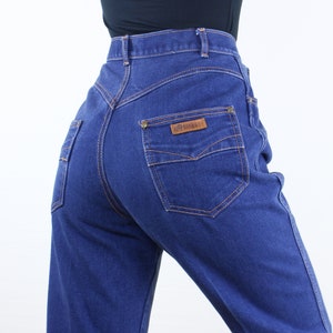 May include: A pair of high-waisted blue denim jeans with a brown leather patch that says "C.P. Harris" on the back pocket.