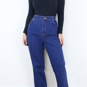 May include: A person wearing a black turtleneck shirt and blue high-waisted jeans. The jeans have a straight leg and are a dark blue wash.