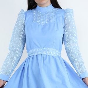 May include: A light blue dress with white lace detailing on the sleeves and neckline. The dress has a fitted bodice and a full skirt.