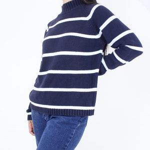 May include: A navy blue and white striped sweater with a mock neck and long sleeves.