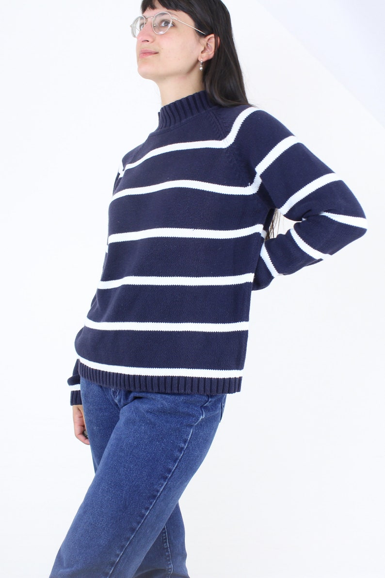 May include: A navy blue and white striped sweater with a mock neck and long sleeves.