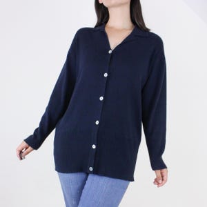 May include: A navy blue long-sleeved cardigan with a collared neckline and button closure.
