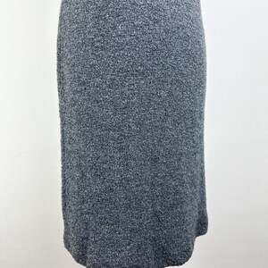 May include: A gray knit midi dress with a simple, fitted silhouette. The dress is made of a soft, comfortable fabric and has a slightly textured surface.