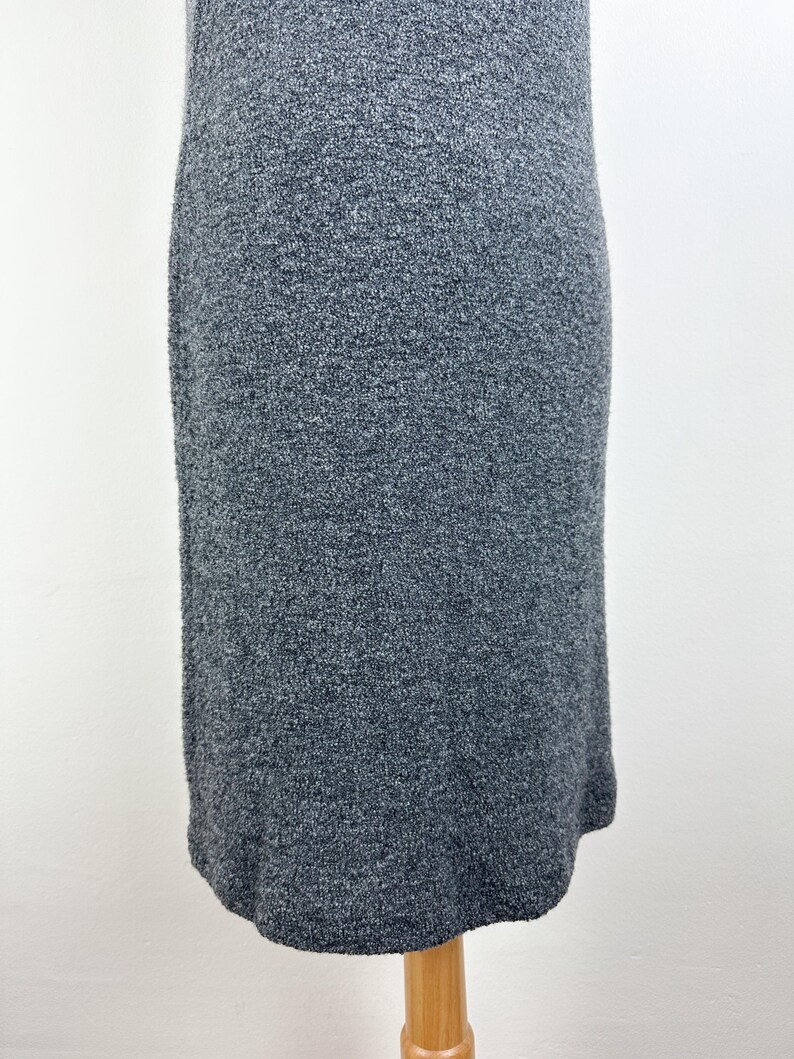 May include: A gray knit midi dress with a simple, fitted silhouette. The dress is made of a soft, comfortable fabric and has a slightly textured surface.