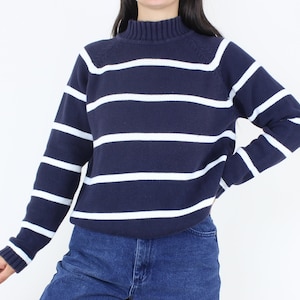 May include: A navy blue and white striped sweater with a mock neck.