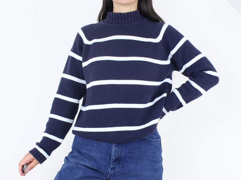 May include: A navy blue and white striped sweater with a mock neck.