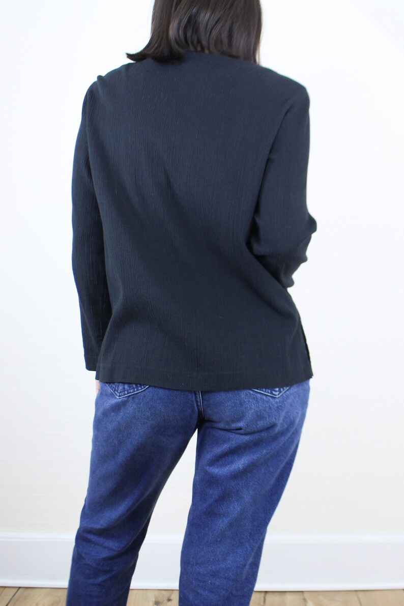 May include: A dark blue long-sleeved shirt with a relaxed fit. The shirt is made of a soft, textured fabric. The model is wearing the shirt with blue jeans.