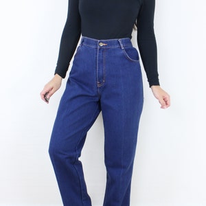 May include: A person wearing a black turtleneck shirt and blue high-waisted jeans. The jeans have a straight leg and are a dark wash.