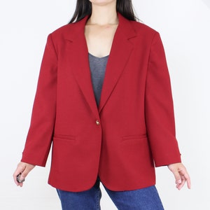May include: A red blazer with a single gold button closure. The blazer has a classic, tailored fit and features two pockets.