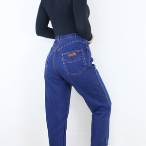 May include: A pair of high-waisted blue denim jeans with a brown leather patch on the back pocket.