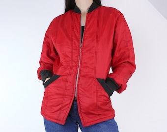 May include: A red quilted jacket with black zipper and cuffs. The jacket has a zipper closure and two pockets.