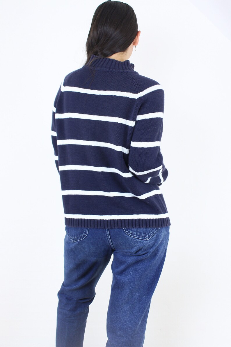 May include: A navy blue and white striped sweater with long sleeves. The sweater has a mock neck and is made of a soft, comfortable material.