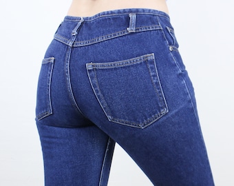May include: A pair of dark blue denim jeans with a back pocket. The jeans are fitted and have a classic style.