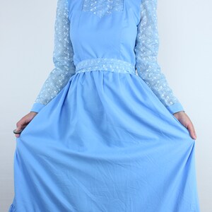 May include: A light blue maxi dress with long sleeves and a white lace overlay. The dress has a high neck and a fitted bodice with a gathered skirt.