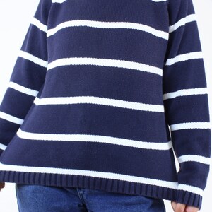 May include: A navy blue and white striped sweater with a mock neck.