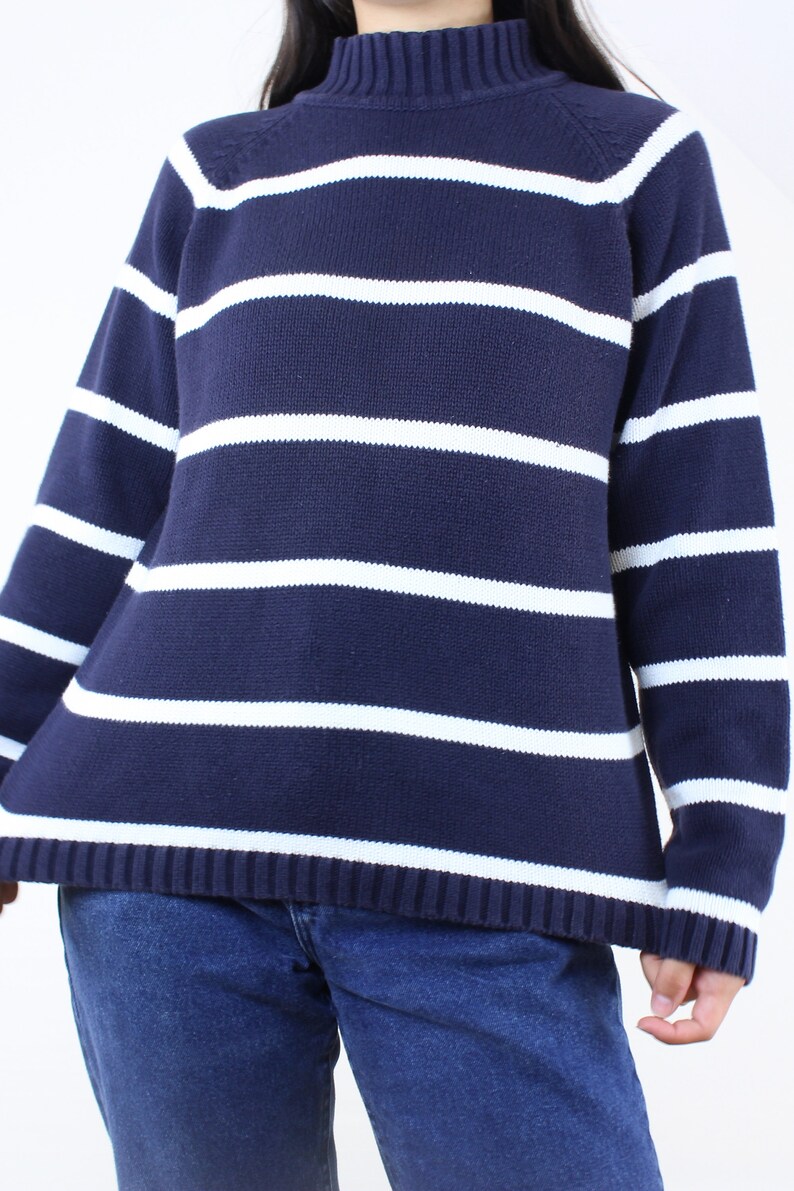 May include: A navy blue and white striped sweater with a mock neck.