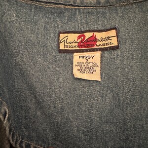 May include: A blue denim vest with a brown label that reads "Gloria Vanderbilt Signature Label" and a white tag that reads "Missy S 100% Cotton Made in Sri Lanka RN 89826 See Reverse for Care".