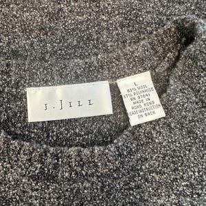 May include: A gray J.JILL sweater tag with the text "J.JILL" and size "L" with the fabric content: 83% wool, 17% polyamide, RN 97641, Made in Hong Kong, Care Instruction on Back.