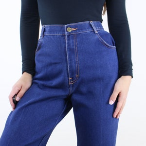 May include: A pair of high-waisted blue denim jeans with a button fly and orange stitching.