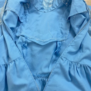 May include: A light blue dress with a zipper closure and a white embroidered neckline.