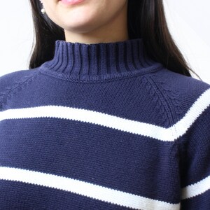 May include: A navy blue and white striped sweater with a mock neck.