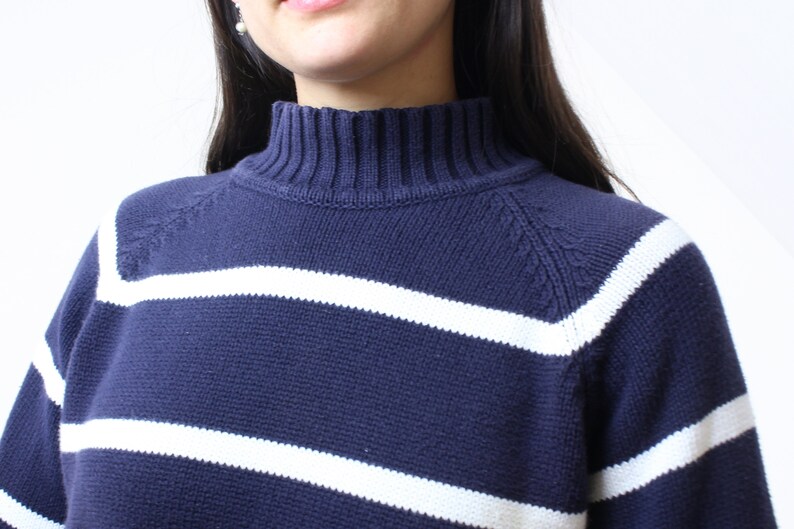 May include: A navy blue and white striped sweater with a mock neck.
