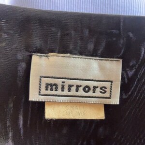 May include: A white tag with black text that reads "mirrors" on a black fabric background. The tag also has a smaller white tag that reads "Small Size Over".