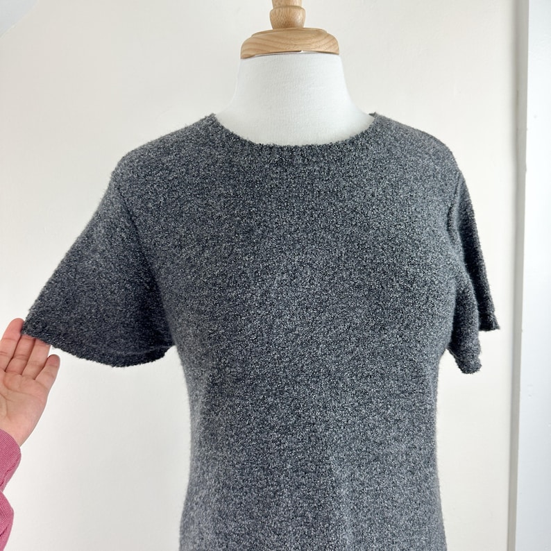 May include: A gray short-sleeved sweater dress with a round neckline.