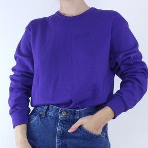 May include: A purple long-sleeved sweatshirt with a crew neck.