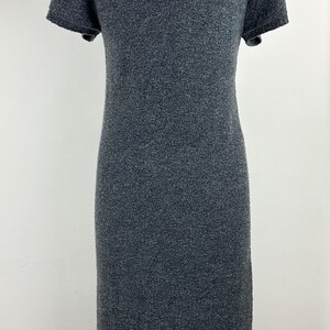 May include: A gray short-sleeved dress with a textured knit fabric. The dress is on a wooden mannequin.