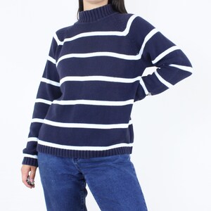 May include: A navy blue and white striped sweater with a mock neck.