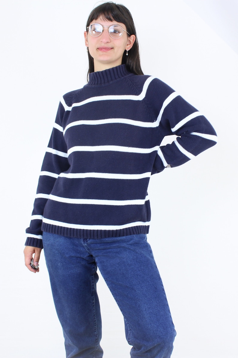 May include: A navy blue and white striped sweater with a mock neck.