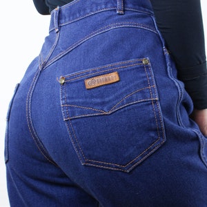 May include: A pair of dark blue denim jeans with a brown leather patch that says "GITANO" on the back pocket.