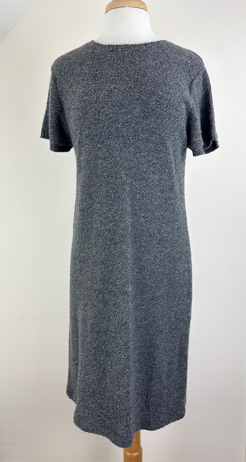 May include: A gray short-sleeved sweater dress with a textured knit fabric.
