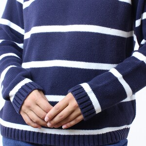 May include: A navy blue and white striped sweater with long sleeves. The sweater is made of a soft, knitted fabric.