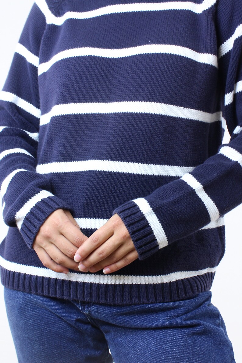 May include: A navy blue and white striped sweater with long sleeves. The sweater is made of a soft, knitted fabric.