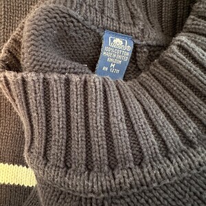 May include: A black and white striped sweater with a blue tag that reads "100% cotton made in United Kingdom M RN 13711".