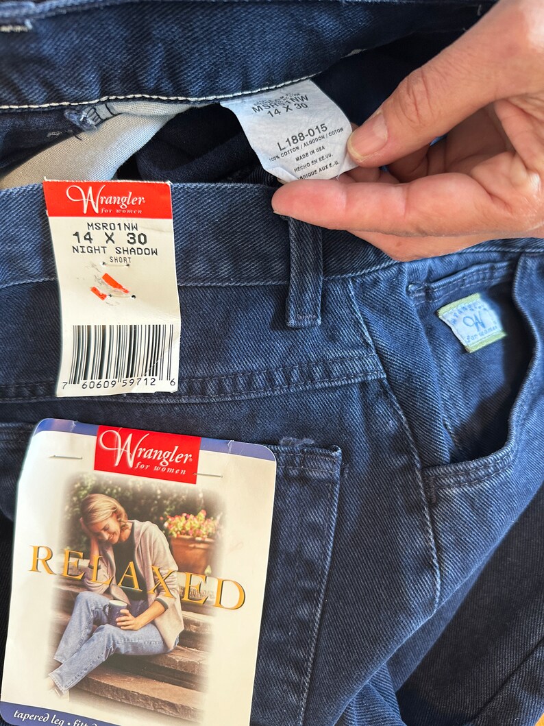 Może przedstawiać: Dżinsy z ciemnoniebieskiego denimu z metką Wrangler. Na metce widnieje napis "MSRO1NW 14 X 30 NIGHT SHADOW SHORT". Dżinsy mają luźny kr&oacute;j i zwężane nogawki.